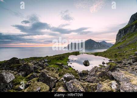 Les nuages roses du soleil de minuit reflétée dans la mer froide, Flakstad, Moskenesoya, comté de Nordland, îles Lofoten, Norvège Banque D'Images