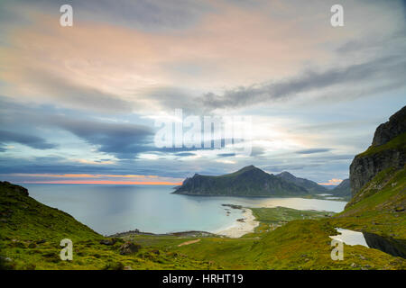 Les nuages roses du soleil de minuit reflétée dans la mer froide, Flakstad, Moskenesoya, comté de Nordland, îles Lofoten, Norvège Banque D'Images