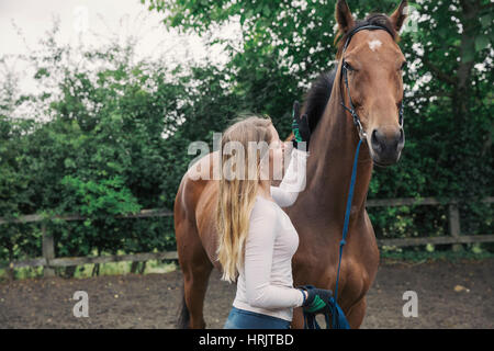 Une jeune femme et d'une baie dans un enclos de chevaux de pur-sang Banque D'Images
