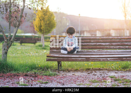 Sad boy sitting in the park Banque D'Images