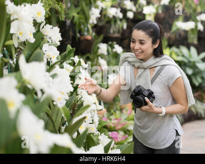 Jeune femme affichage des orchidées tropicales au centre DREAM, le Jardin Botanique à Ocean Expo Park, Nago, Okinawa, Japon Banque D'Images