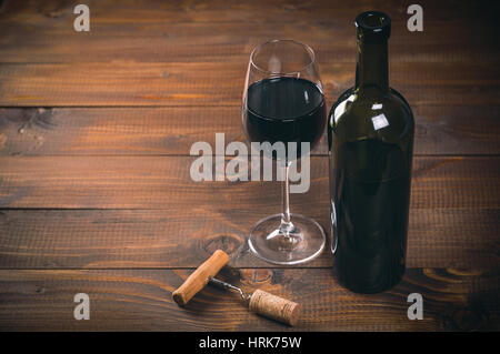 Bouteille de vin rouge et en verre, tire-bouchons et bouchons sur table en bois Banque D'Images