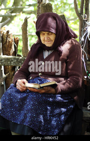 RAMETI, ROUMANIE - juin 6, 2010 : femme aîné lire la Bible. Les générations plus âgées dans les zones rurales de la Roumanie sont très religieux Banque D'Images