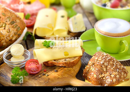 Copieux petit déjeuner avec une tasse de Cappuccino, rouleaux de fromage et un grand choix de nourriture Banque D'Images