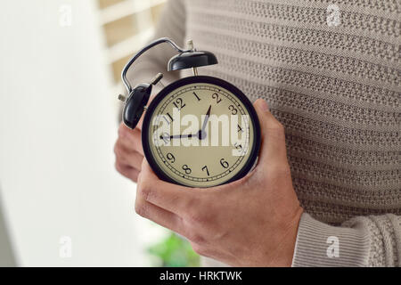 Gros plan du young Caucasian man l'enroulement ou le réglage de l'heure d'un réveil Banque D'Images