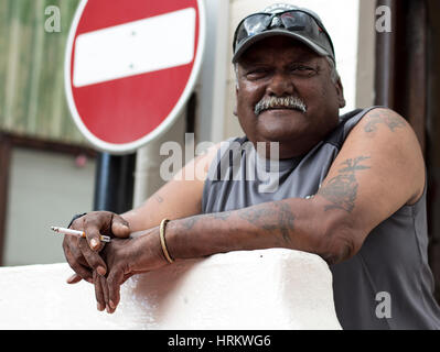 Homme avec moustache tenant une cigarette. Une mauvaise façon signe est derrière lui. Banque D'Images