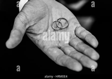 Les anneaux de mariage tenue par le marié Banque D'Images