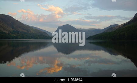 Buttermere lake, Lake District, Cumbria à vers Fleetwith brochets avec nuages ciel et montagnes reflétées dans les eaux calmes d'une soirée d'été Banque D'Images
