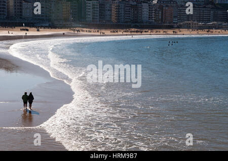 Pays Basque : deux personnes marchant sur la plage de La Concha, considérée comme l'une des meilleures plages de la ville en Europe, à Donostia San Sebastian Banque D'Images