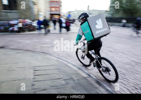 Un Deliveroo courier livraison de nourriture s'engouffre dans le centre de Cambridge UK Banque D'Images