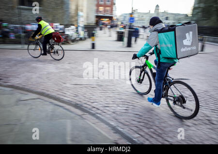 Un Deliveroo courier livraison de nourriture s'engouffre dans le centre de Cambridge UK Banque D'Images