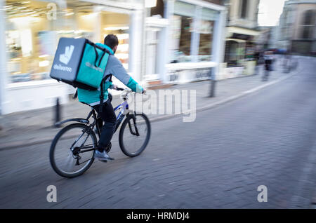 Un Deliveroo courier livraison de nourriture s'engouffre dans le centre de Cambridge UK Banque D'Images