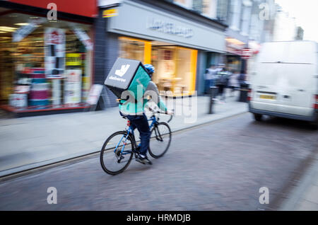 Un Deliveroo courier livraison de nourriture s'engouffre dans le centre de Cambridge UK Banque D'Images