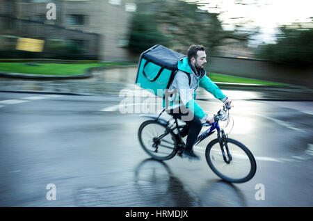 Un Deliveroo courier livraison de nourriture s'engouffre dans le centre de Cambridge UK Banque D'Images