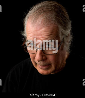 Close up portrait of head shot of a senior man dans ses 50 ans. homme portant des T-shirt noir et isolé sur fond noir. Banque D'Images