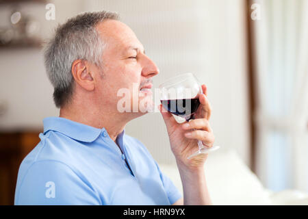 Homme mature jouissant d'un verre de vin rouge Banque D'Images