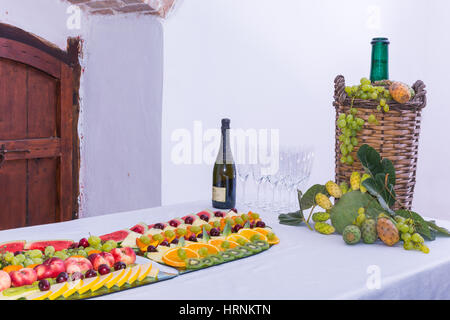 Composition de fruits et couper le verre demijohn vin couché pour l'osier. Sur une table laden avec un restaurant, avec des raisins, des figues, de figuiers de barbarie et de feuilles. Un Banque D'Images