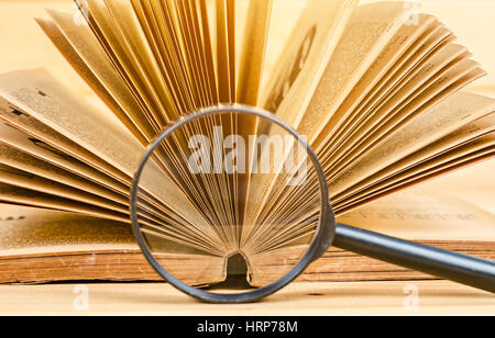 Loupe et vieux livre sur fond de bois. Banque D'Images