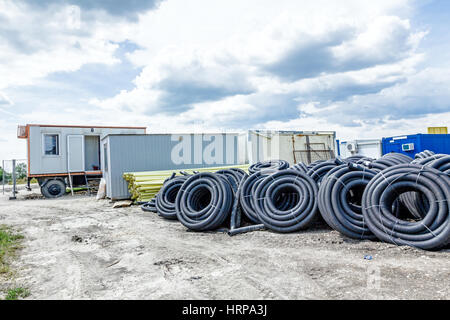 Matériel de stockage de fortune, PEHD et tuyaux de PVC pour usage différent au chantier de construction de l'entrepôt improvisé. Banque D'Images