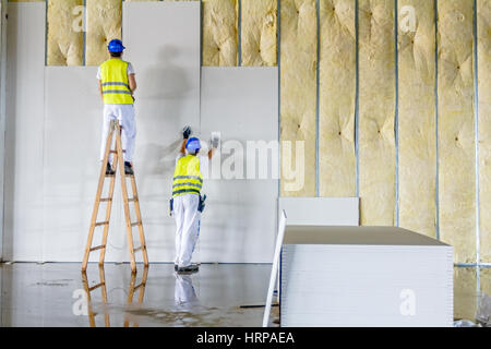 Les travailleurs sont assemblée générale mur de gypse. Plâtre est en construction à l'aide d'échelle en bois. Banque D'Images