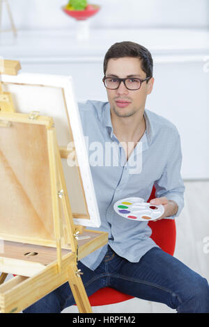 Jeune homme artiste peint sur toile avec des peintures à l'huile Banque D'Images