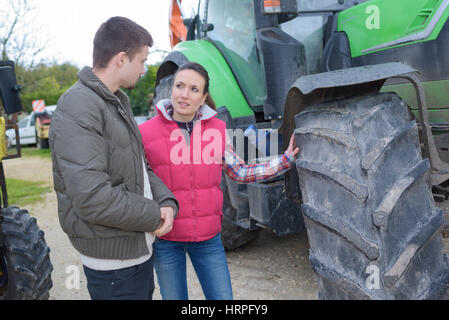 Jolie femme vendant tout nouveau tracteur pour agriculteur débutant Banque D'Images