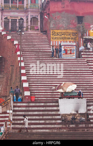 Un homme balaie les étapes d'une scène au petit matin à Vijayanagaram ghat au-dessus d'une zone de baignade hindou sur les bords du Gange à Varanasi, Inde Banque D'Images