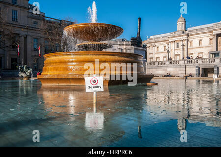 Fontaine à Trafalgar Square, Londres, Royaume-Uni, avec de la glace sur l'eau en hiver. Ciel bleu vif Banque D'Images