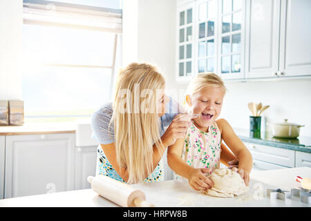 Rire petite fille aider sa mère pétrir de la pâte qu'ils travaillent ensemble dans la cuisine pâtisseries dessert pour le dîner , high key with copy space Banque D'Images