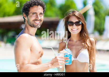 Heureux couple having cocktails dans la piscine Banque D'Images