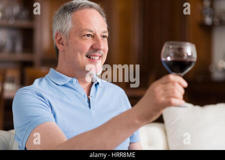 Portrait d'un homme mûr bénéficiant d''un verre de vin rouge à la maison Banque D'Images