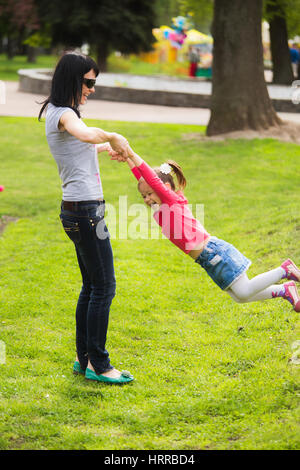 Famille heureuse de la maman et sa fille gaiement tourner autour de ensemble. Peu drôle fille de 4 ans, l'âge joue à l'extérieur avec sa mère à spring city pa Banque D'Images