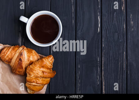 Café et croissants sur la table noire, vue du dessus Banque D'Images