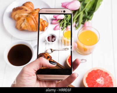 Woman's hand taking photo de délicieux breakfst avec smartphone close-up Banque D'Images