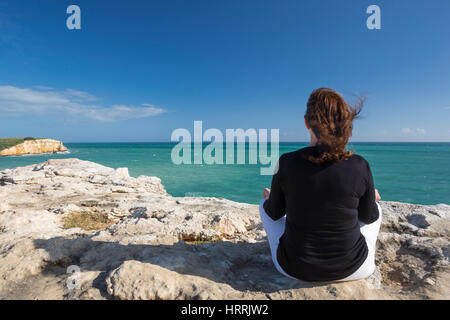 WOMAN MEDITATING ON CLIFF TOP EN POSITION DE YOGA FACE À LA MER Cabo Rojo, PUERTO RICO Banque D'Images