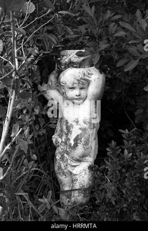 Statue de chérubin noir et blanc dans le jardin tropical Banque D'Images