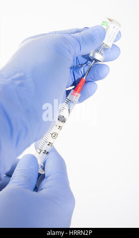 Close up d'anesthésiologistes les mains gantées de retrait du médicament générique, l'ondansétron pour la nausée, dans la seringue avec aiguille de sécurité. Arrière-plan blanc. Banque D'Images