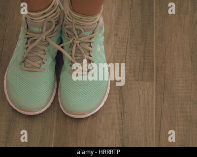 Femme portant des chaussures de sport vert clair sur plancher en bois Banque D'Images