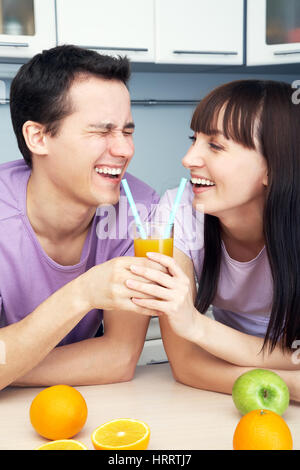 Young cheerful couple boire le jus d'orange dans la cuisine. une saine alimentation Banque D'Images