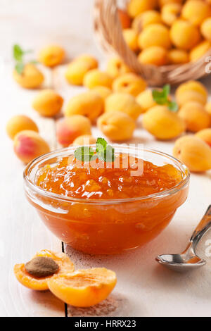 Confiture d'abricot dans un bol en verre , abricots frais sur fond de bois Banque D'Images