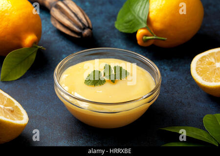 Le lait caillé de citron dans un bol en verre, de citrons frais, centrifugeuse, sur un fond bleu Banque D'Images