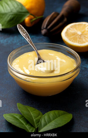 Le lait caillé de citron dans un bol en verre, de citrons frais, centrifugeuse, sur un fond bleu Banque D'Images