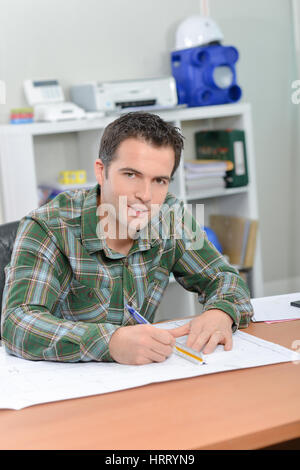 Homme assis au bureau à travailler sur des dessins à l'échelle Banque D'Images