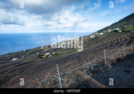 Vignes, Fuencaliente. La Palma. Une vue sur la montagne, les vignobles où les vignes poussent dans le riche sol de lave. Ils produisent une variété de vins dans cette région et leur variété la plus connue est le Malvasia. Un village local peut être vu au-delà des vignobles. À cette altitude la vapeur d'eau du nuage est visible longeant la côte. C'est un jour lumineux jour brumeux avec plusieurs nuages en mouvement rapide. Banque D'Images