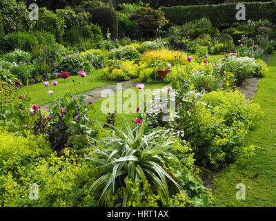 Chenies Manor jardin en contrebas en été avec les dahlias et les plantes à feuillage vert luxuriant autour de l'étang ornemental et frontières herbacées ; chemins herbeux. Banque D'Images
