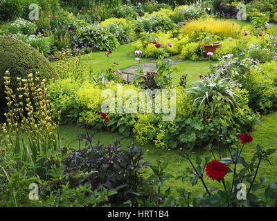 Chenies Manor jardin en contrebas en été avec les dahlias et les plantes à feuillage vert luxuriant autour de l'étang ornemental et frontières herbacées ; chemins herbeux. Banque D'Images
