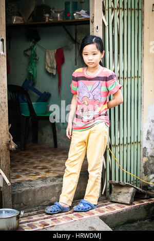 Hanoi, Vietnam - le 26 avril 2014 : Portrait de fille vietnamienne avec chien à l'entrée de sa maison sur la rue de Hanoï au Vietnam, le 26 avril 2014. Banque D'Images