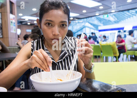 Femme mangeant le déjeuner avec des baguettes dans un restaurant. Asian girl eating traditionnels de la cuvette. Banque D'Images