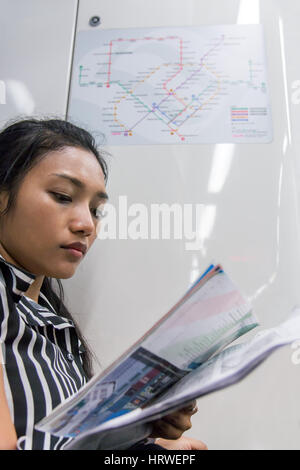 L'asiatique se penche sur les cartes dans le métro. Une femme lisant plan de transport urbain. Fille va en train et l'étude des cartes avec des notes. Banque D'Images