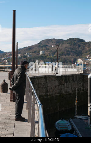 Un homme avec le béret dans le port à l'horizon de la vieille ville sur le front de mer de Donostia San Sebastian, la ville côtière sur le golfe de Gascogne Banque D'Images